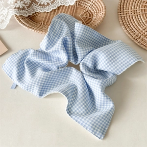 Detail of blue and white gingham hair scrunchie with soft fabric pleats and breathable texture