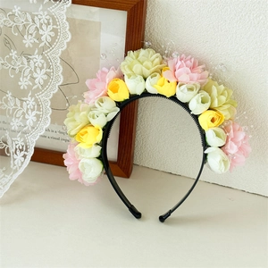 Dettaglio del cerchietto floreale con fiori finti rosa e gialli e perle di cristallo