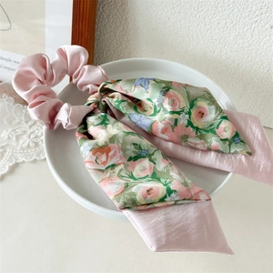 Detail of pink satin scrunchie with floral bow streamer on a white ceramic plate