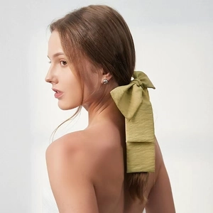 Detail of elegant olive green oversized bow hair tie with long ribbons on model