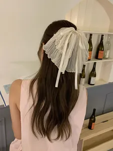 Détail d'un chouchou noeud géant crème avec couches de dentelle et perles blanches