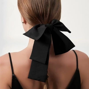 Elegant black silk oversized bow hair tie with long ribbons on a female model