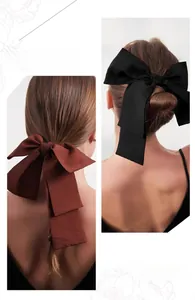 Detail showing elegant long ribbon bow clips in black and brown fabric texture