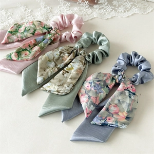 Close-up of floral ribbon scrunchies set in pink, green, and blue satin fabric