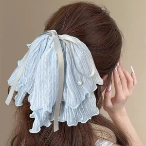 Chouchou plissé bleu clair avec perles et rubans élégants sur de longs cheveux bouclés