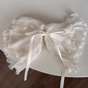 Detail of white pleated fabric hair scrunchie with pearls and delicate bow accent