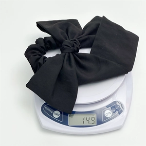 Detail shot showing the lightweight 14.9g weight of the black fabric bow hair tie