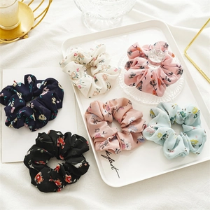 Detail of assorted floral chiffon scrunchies in various colors on a white display tray