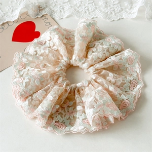 Détail du chouchou en dentelle rose avec broderie florale délicate et maille multicouche
