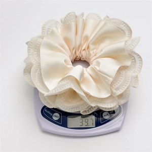 Detail shot of a cream satin scrunchie with lace edges on a digital scale weighing 39.7g