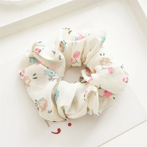Detailed macro view of the floral chiffon fabric texture and pleats on a scrunchie