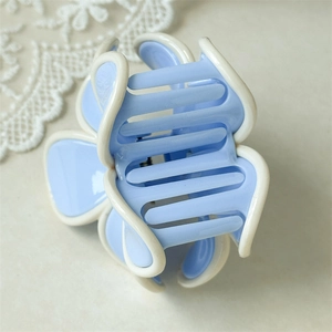Détail de la pince à cheveux fleur bleu clair avec bordure blanche et design à dents croisées