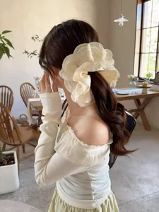 Close-up of a large cream ruffled hair scrunchie with lace edges on a model's ponytail