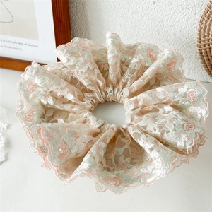Détail de la broderie florale sur chouchou en dentelle beige aux bords festonnés