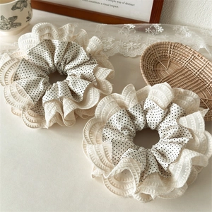 Close-up of layered lace and polka dot fabric scrunchies with elegant ruffled texture