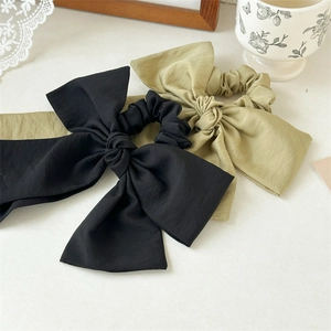 Detailed texture of large fabric bow scrunchies in black and olive green colors