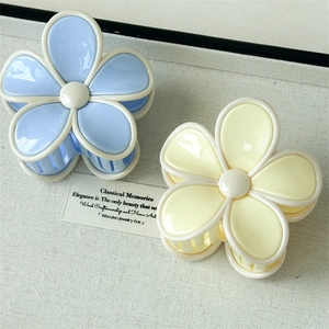 Détail de pinces à cheveux fleurs en acrylique bleu et jaune crème avec bordure beige