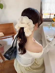 Close-up of a layered cream lace scrunchie with scalloped embroidery on a ponytail