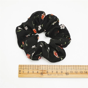 Detail view of a floral chiffon hair scrunchie with a scale showing 11cm diameter size