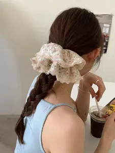 Détail d'un chouchou en dentelle brodée à motif floral sur une coiffure tressée