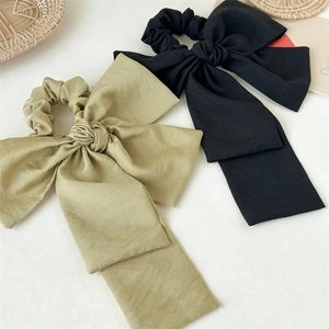 Detailed macro view of elegant black and moss green chiffon bow hair ties with long ribbons