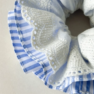 Close-up of blue and white striped fabric scrunchie with delicate white lace edge