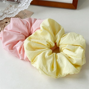 Detail view of large pastel pink and yellow scrunchies with soft pleated fabric textures