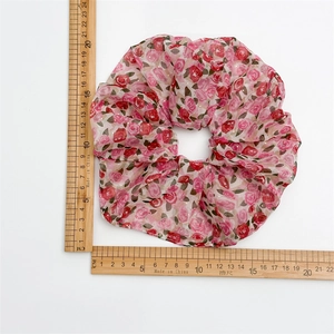 Grand chouchou en mousseline avec roses roses et paillettes dorées sur fond blanc