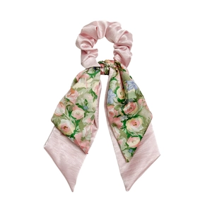 Light pink satin hair scrunchie with long floral print ribbons on a white background