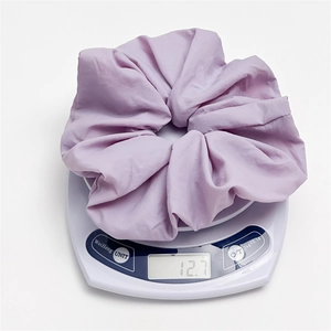 Detail shot showing a light purple scrunchie on a scale weighing 12.7 grams for hair styling