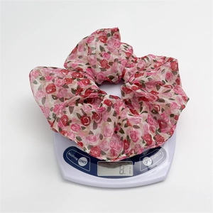 Détail d'un chouchou en mousseline rose à motif floral orné de paillettes dorées