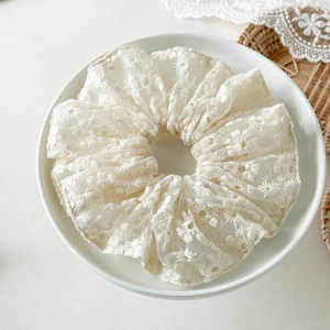 Détail du chouchou en dentelle blanc crème avec broderie marguerite sur tissu transparent