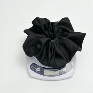 Detailed view of large black satin scrunchie weighing approximately 35.3g on a scale