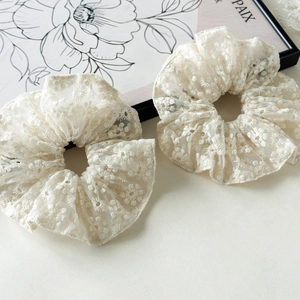 Détail de la broderie florale en dentelle blanche sur les chouchous à haute élasticité