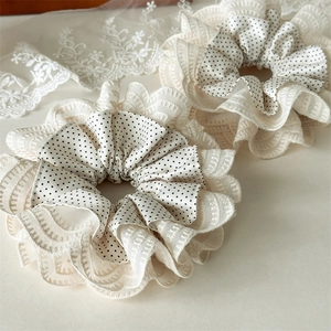 Close-up of double-layered lace scrunchie with white polka dots and elegant ruffled edges