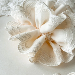 Detailed macro view of cream satin hair scrunchie with delicate lace embroidery edges
