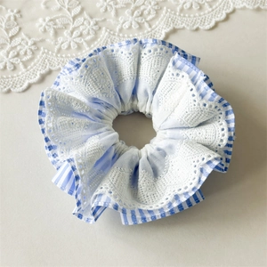 Close-up of blue striped scrunchie featuring elegant white crocheted lace edging detail