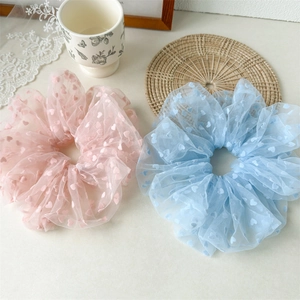 Macro shot of pink and blue mesh hair scrunchies with sweet heart patterns on white table