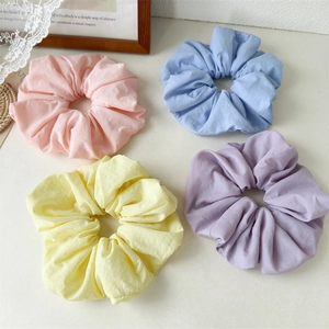 Set of four fluffy macaron colored sponge hair scrunchies on a white minimalist background