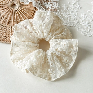 Vue détaillée du chouchou en dentelle crème avec broderie florale et texture délicate