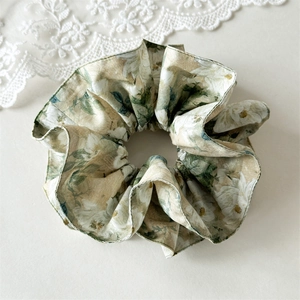 Close-up of premium layered floral scrunchie with delicate white flower patterns and rich texture