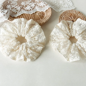 Détail d'un chouchou en tulle blanc avec broderie florale délicate et dentelle fine