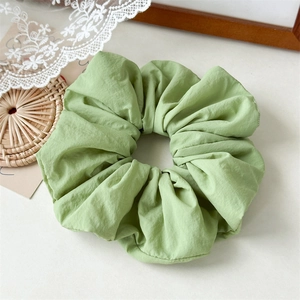 Close-up of light green oversized pleated hair scrunchie with soft fabric texture