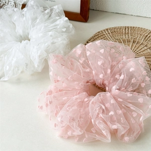 Close-up of pink and white mesh hair scrunchies with fuzzy heart patterns and texture