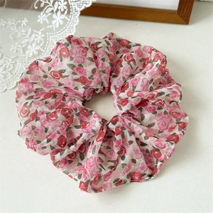 Détail d'un chouchou en mousseline avec motifs roses rouges et paillettes dorées