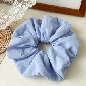 Detail of light blue pleated sponge hair scrunchie on white lace background
