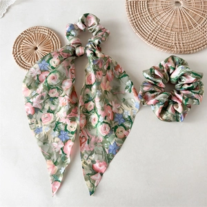 Detailansicht grüner Blumen-Scrunchies mit langen Bändern auf einer gewebten Matte