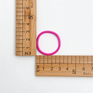 Detail showing a seamless dark pink elastic hair tie measuring 3cm on a wooden ruler scale