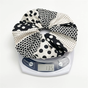 Large black and white polka dot scrunchie on electronic scale showing 13.5g weight