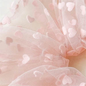 Macro shot of high-quality pink mesh fabric with soft 3D flocked heart patterns